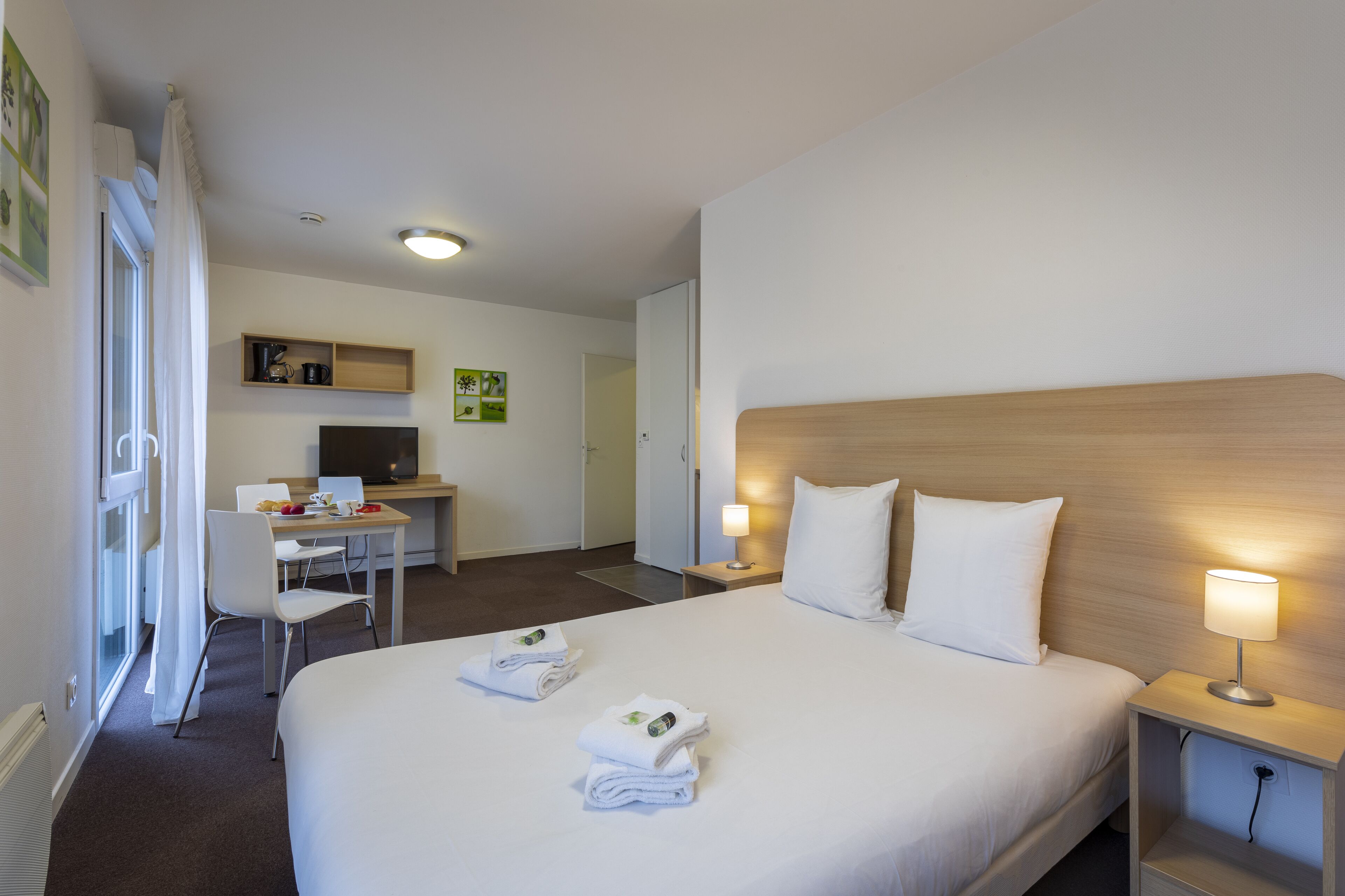 Une chambre d’hôtel avec un lit, des tables de chevet, un bureau et une chaise.