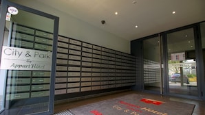 A hotel entrance with a large display of storage boxes, a welcome mat, and a sign indicating the hotel is by the city and park. - KOSY Appart'Hôtels Troyes - City & Park (Troyes)
