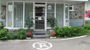 A building with a stone facade, a covered entrance, and potted plants. - Motel Jann (Québec City)
