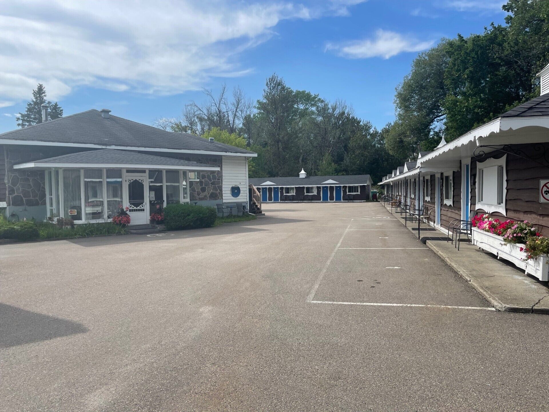 Een motel met een overdekte parkeerplaats, een stenen gebouw en een rij cabines met blauwe deuren.