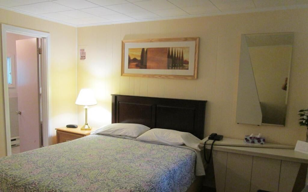 Ein Hotelzimmer mit Bett, Nachttischlampe, Schminktisch und einem Bild an der Wand.