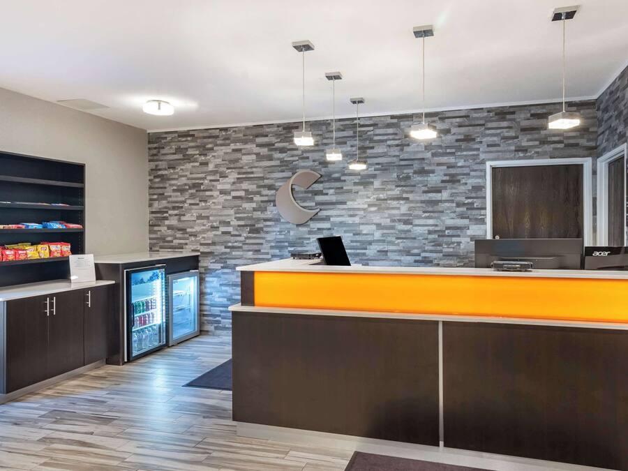 A modern reception area with a stone wall, a refrigerator, and a counter with a computer.