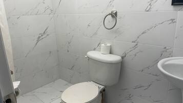 A bathroom with a toilet, a sink, and marble-patterned walls.
