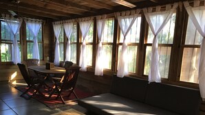 Quarto com teto de madeira, sofá, mesa e cadeiras.