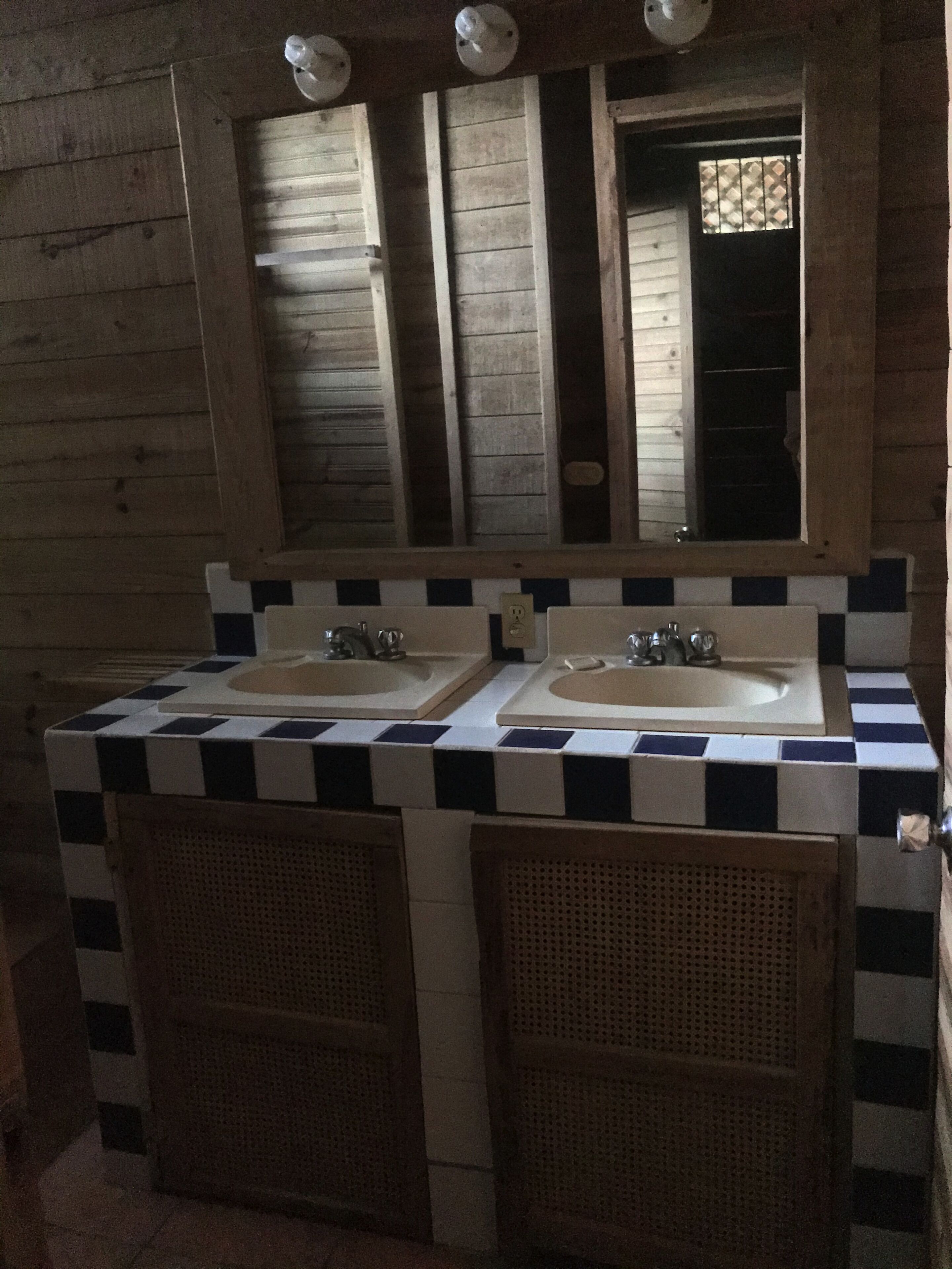 A bathroom with two sinks, a mirror, and a checkered tile backsplash.