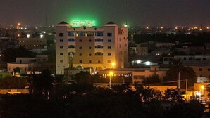 A hotel with a prominent sign, multiple floors, and a surrounding urban area at night. - Royal Suites (Nouakchott)