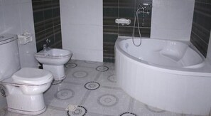 A bathroom with a toilet, bidet, and a bathtub. - Royal Suites (Nouakchott)