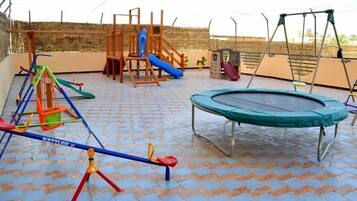 Kids can play on the seesaw, swing set, slide, and trampoline in this outdoor play area.