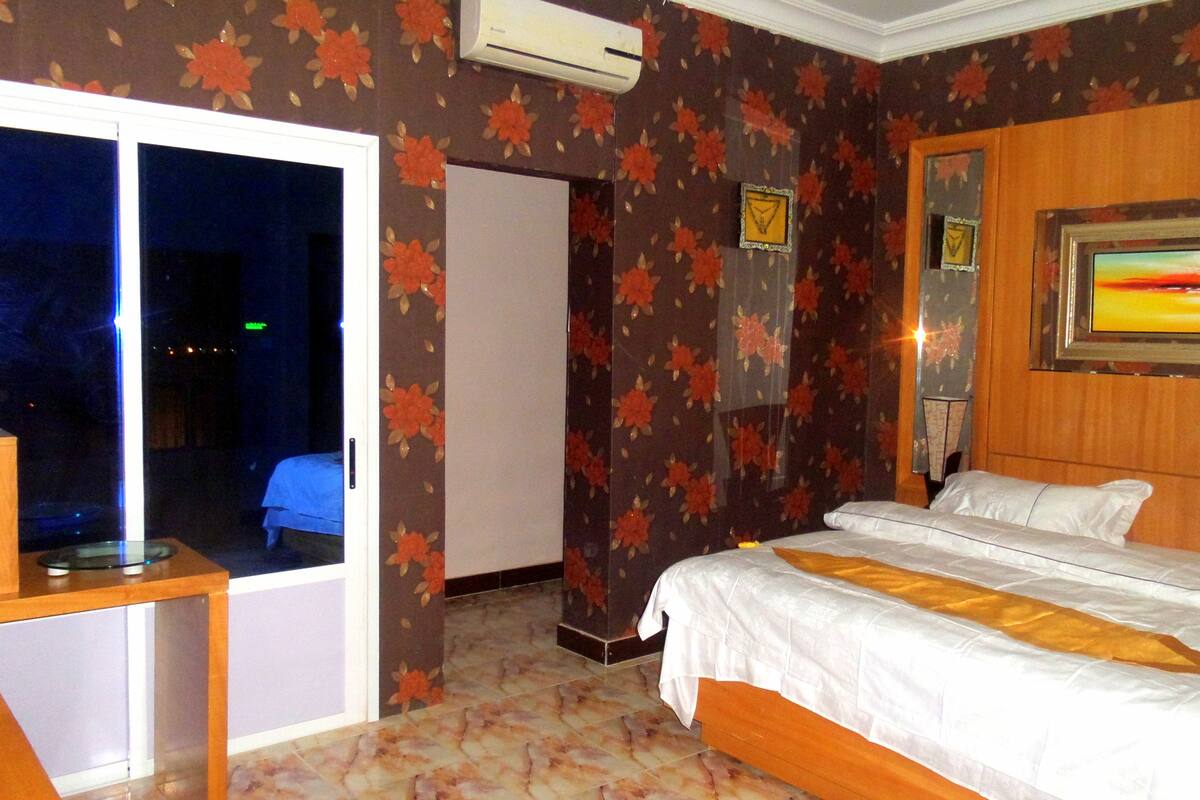 A hotel room with a bed, a desk, and a door leading to a balcony.