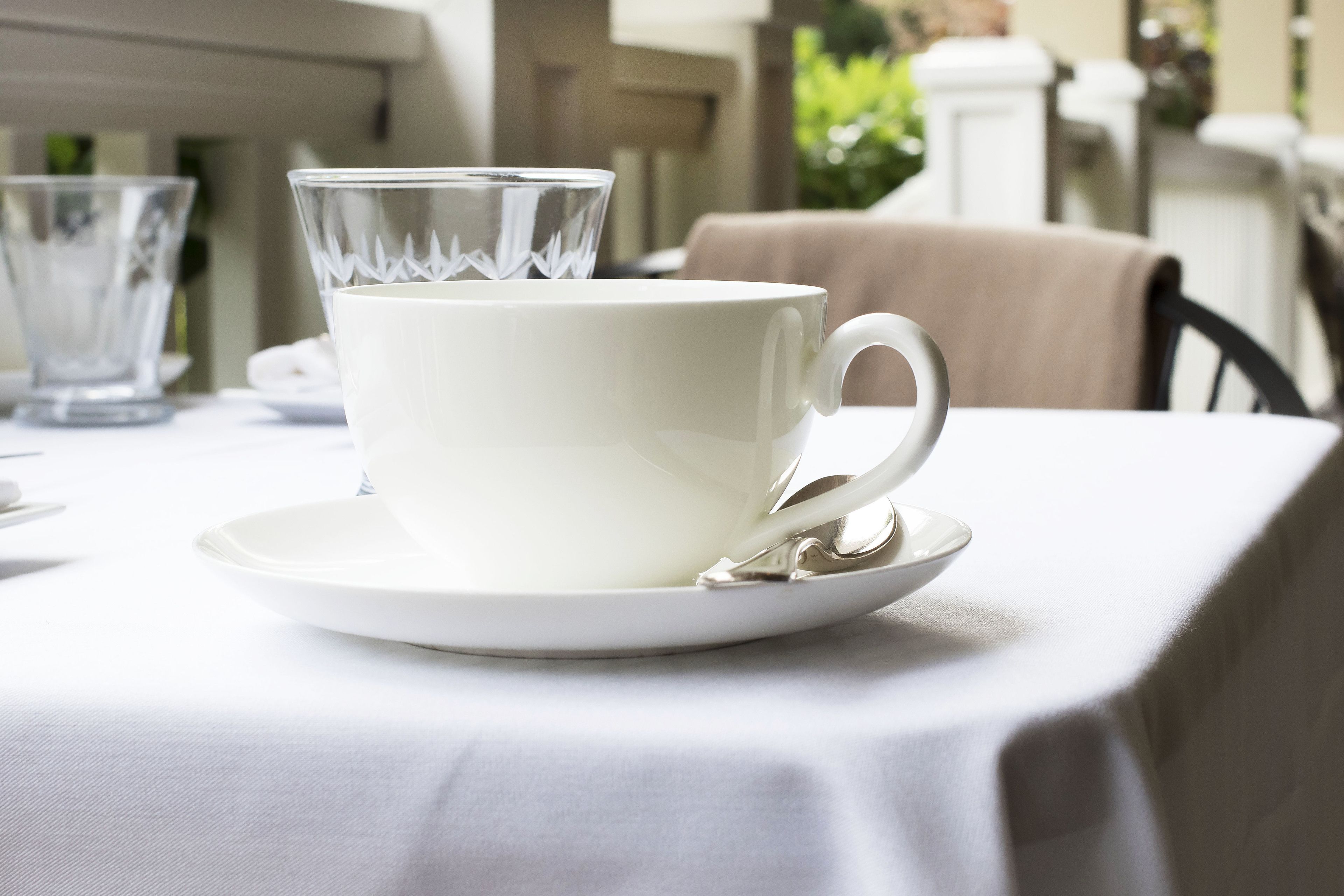 Una taza y platillo blancos sobre una mesa con mantel blanco.