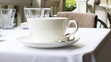 Una taza y platillo blancos sobre una mesa con mantel blanco.