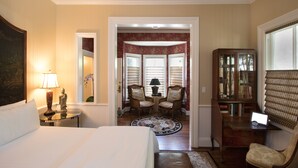 A hotel room with a bed, a desk, a chair, a lamp, a bookshelf, and a view through a door. - Embrace Calistoga (Calistoga)