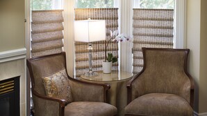 Two upholstered chairs with wooden frames and a small table with a lamp and a potted orchid between them. - Embrace Calistoga (Calistoga)
