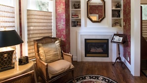 A room with a fireplace, bookshelves, a wicker chair, and a lamp. - Embrace Calistoga (Calistoga)