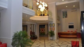 Un vestíbulo de hotel con piso de diseño geométrico, una recepción y una lámpara de araña moderna.