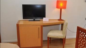 A wooden desk with a television and a lamp.
