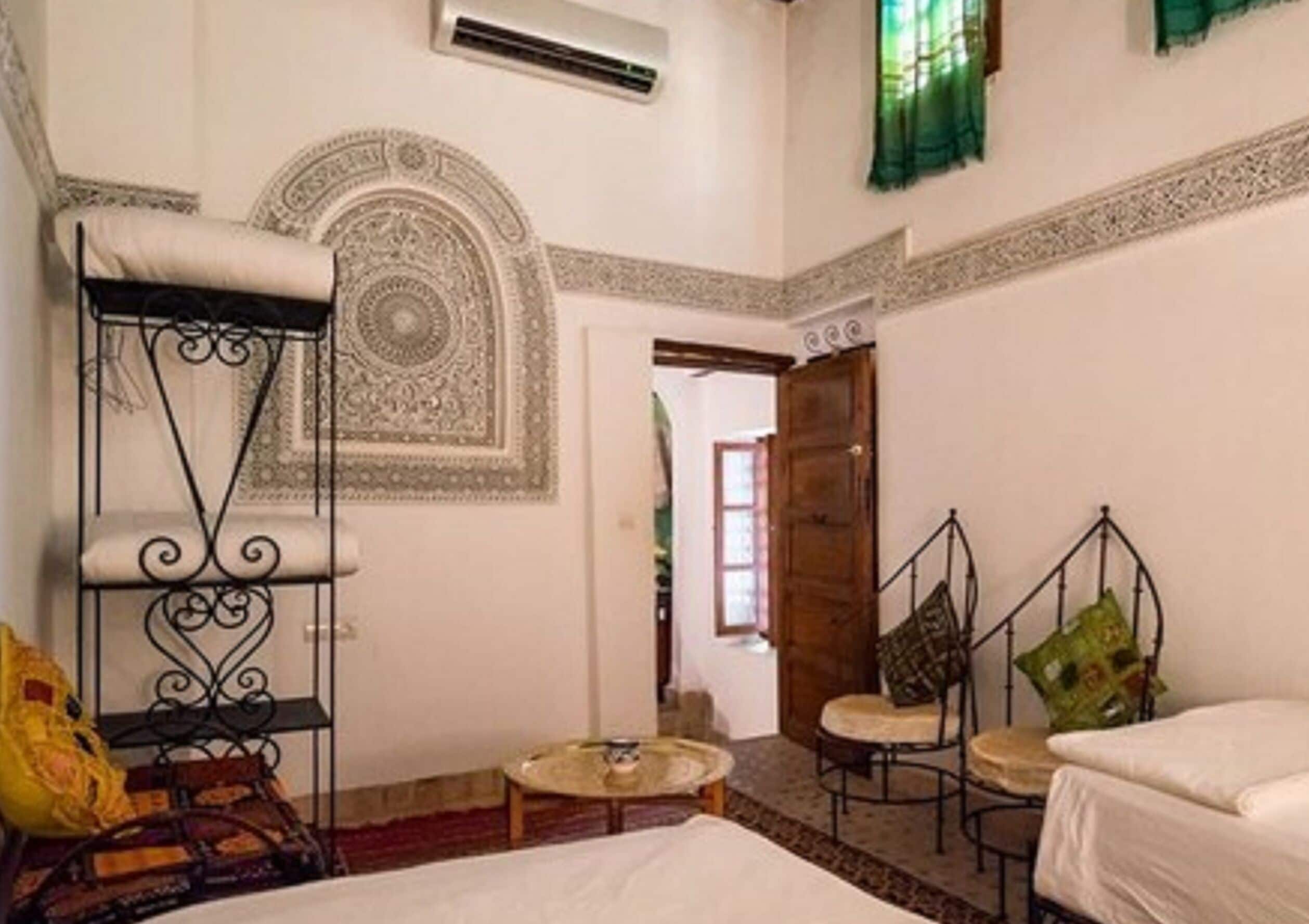 A room with a bed, a small round table, a hanging chair, and a decorative wall pattern.