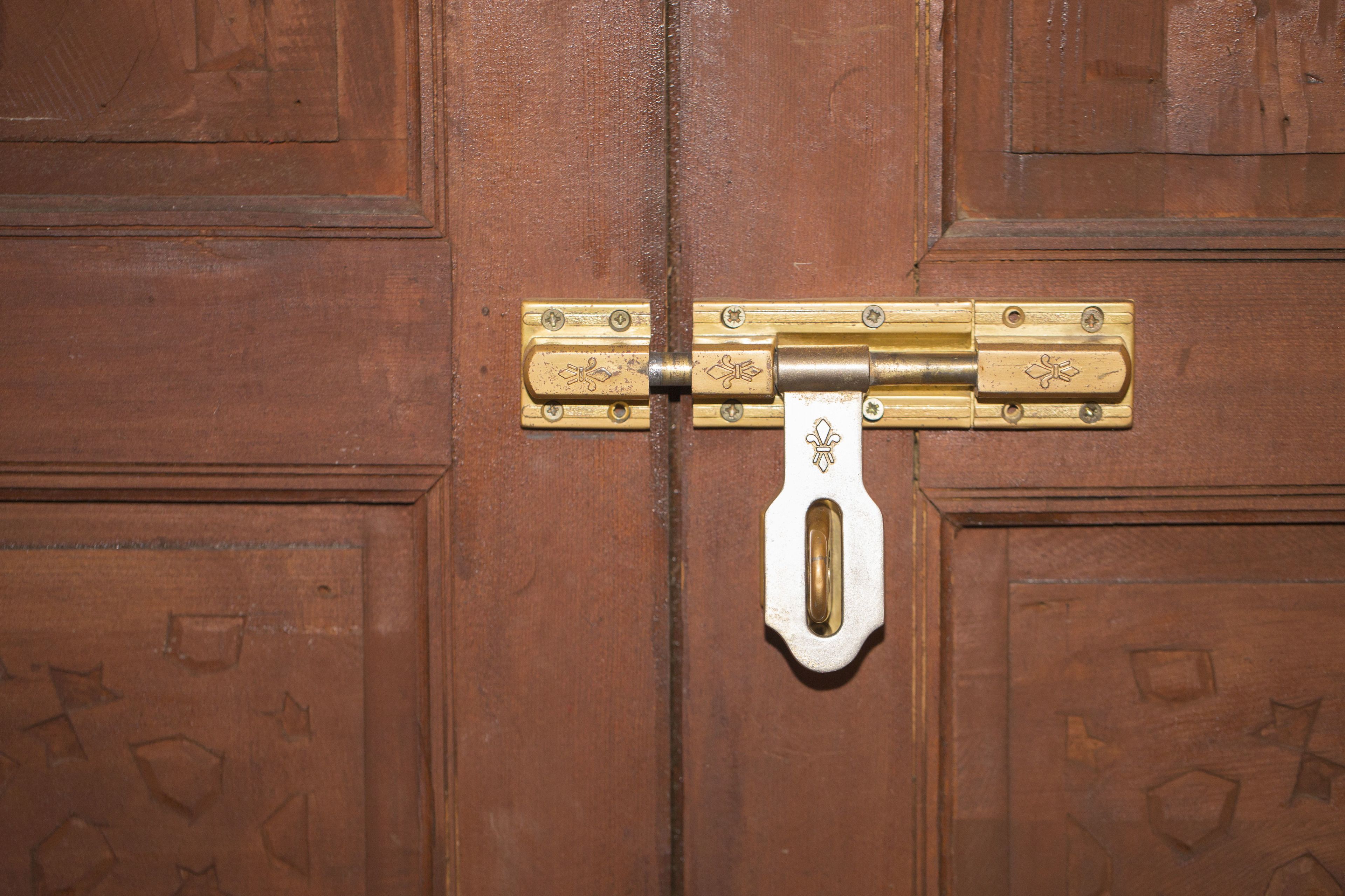 A wooden door with a brass latch and a keyhole.
