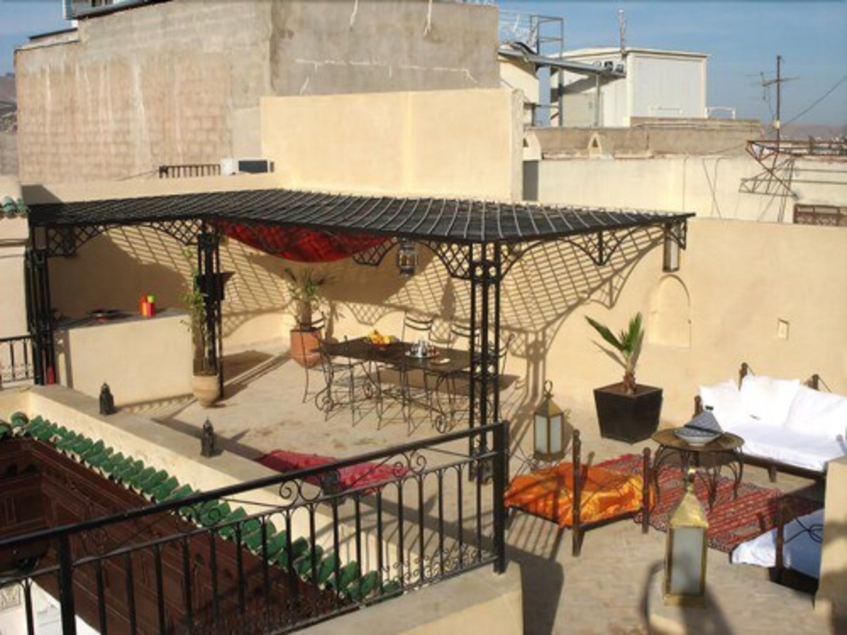 A rooftop terrace with a covered seating area, potted plants, and a table set for dining.