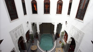 An indoor courtyard with a central pool, ornate arches, and patterned flooring. - Riad Jamaï (Fes)