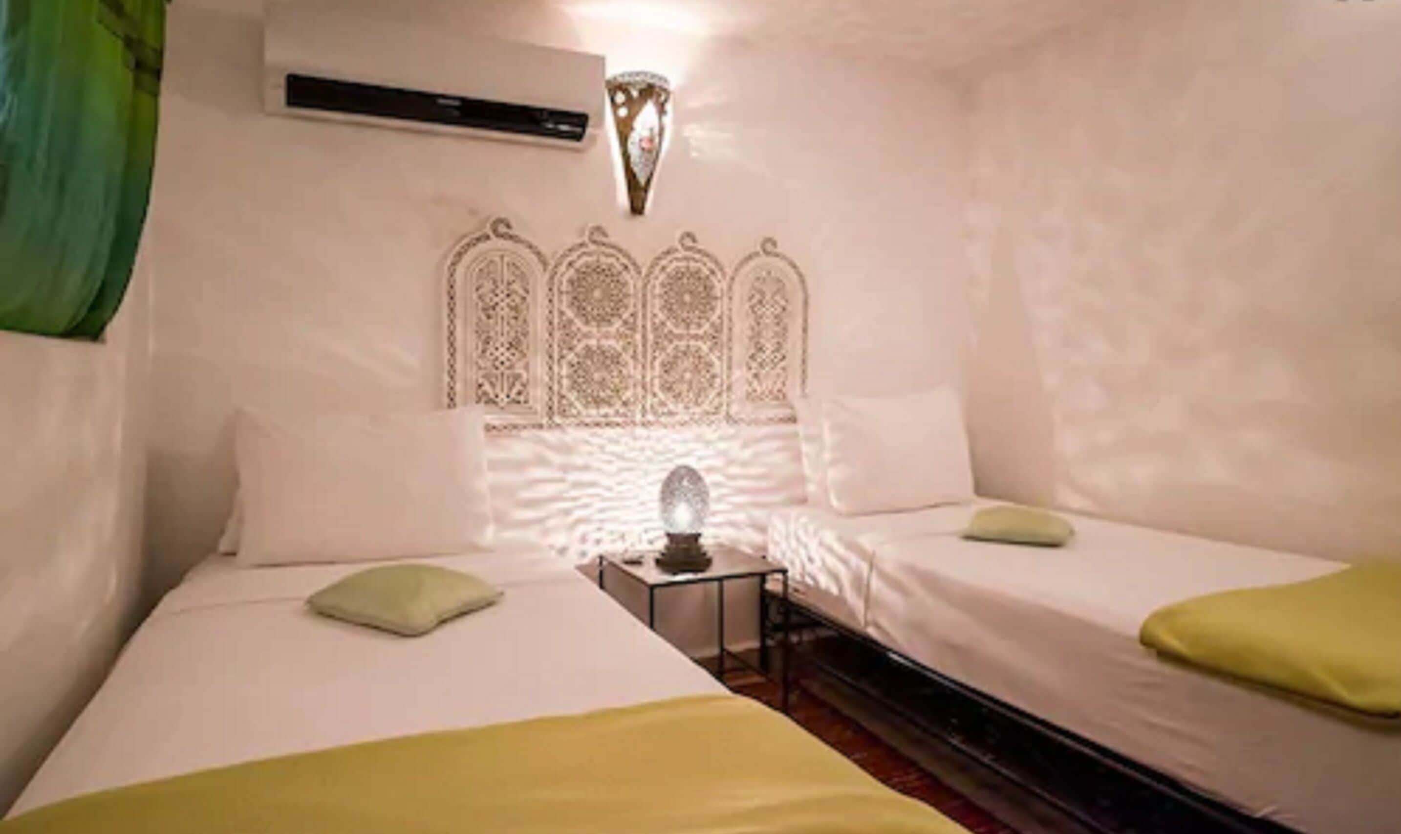 A room with two beds, a nightstand, and a decorative wall piece.