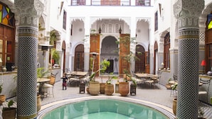 A courtyard with a pool, potted plants, and traditional Moroccan architecture. - Riad Jamaï (Fes)