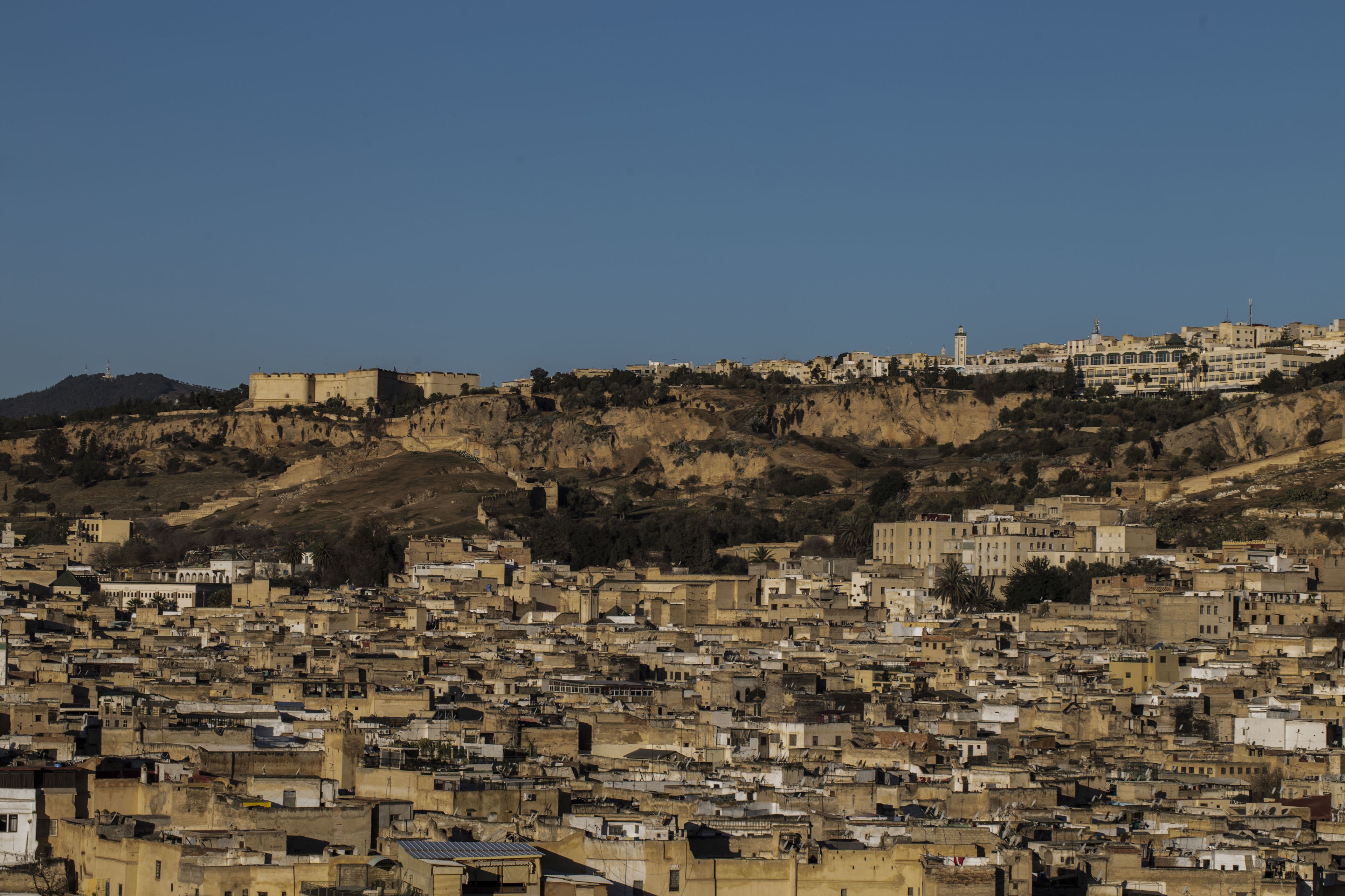 A densely packed urban area with a prominent fort-like structure on a hill, surrounded by residential buildings.