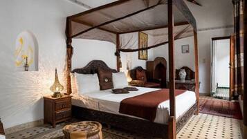 Un lit à baldaquin, une table de chevet avec une lampe et un tapis à motifs.