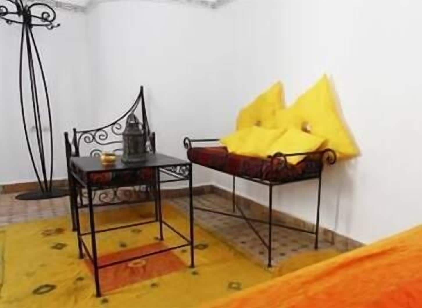 Una habitación pequeña con una cama, una mesa con una silla y una lámpara de pie.