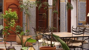 A courtyard with a pool, potted plants, and traditional Moroccan architecture. - Riad Jamaï (Fes)