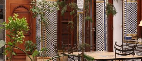 A courtyard with a pool, potted plants, and traditional Moroccan architecture.