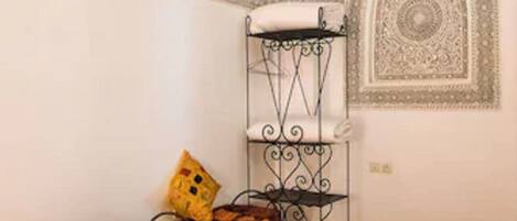 A room with two beds, a small table, a decorative wall piece, and a patterned rug.