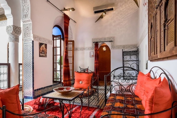 A room with a checkered floor, a metal bed frame, and a table with a bowl. - Riad Jamaï (Fes)