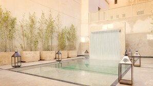 Un área de spa con piscina, plantas de bambú y faroles.