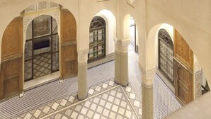 Un interior de varios niveles con arcos, suelo con diseño y vista al cielo nocturno.