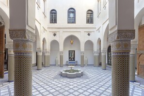 A courtyard with a fountain, arches, and patterned columns. - Palais Bahia Fes (Fes)