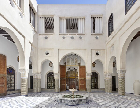 A courtyard with a fountain, arches, and patterned tiles. - Palais Bahia Fes (Fes)