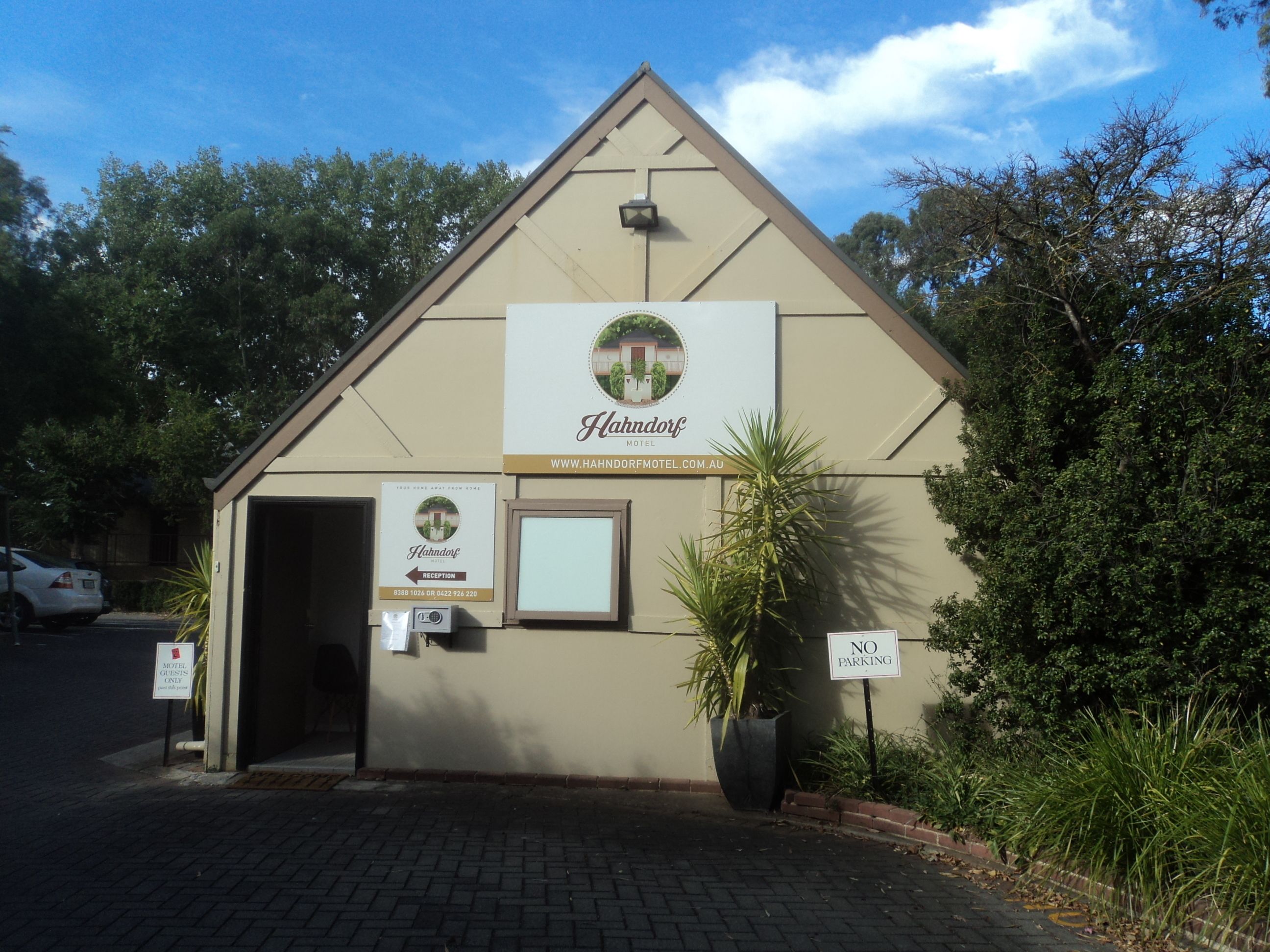 Un edificio pequeño de una sola planta con fachada color beige, un letrero que indica que es el Hahndorf Motel y una zona de recepción.