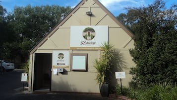 Un edificio pequeño de una sola planta con fachada color beige, un letrero que indica que es el Hahndorf Motel y una zona de recepción.