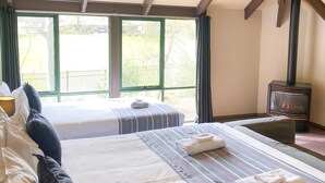 Una habitación de hotel con dos camas, un ventanal grande y una estufa de leña.