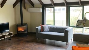 Una sala de estar con chimenea, un sofá, un televisor y un ventanal grande.