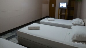 A hotel room with two single beds, a television on a stand, and a wooden wardrobe. - GV Hotel Davao (Davao)