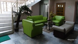A modern interior with a staircase, green sofas, a potted plant, and a chandelier. - GV Hotel Davao (Davao)