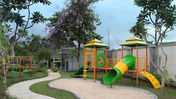 Explore a vibrant play area with a slide and climbing elements, surrounded by a paved walkway and lush gardens.