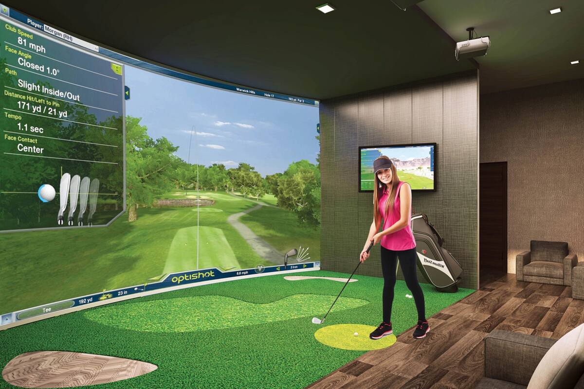 A virtual golf simulation setup with a large screen displaying a golf course, a golf club, and a tee box.
