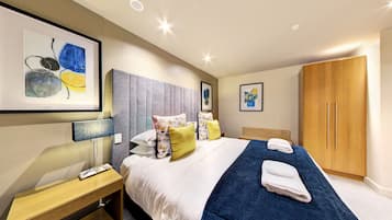 A modern hotel room with a large bed, a wooden wardrobe, and artwork on the walls.