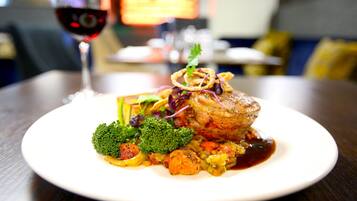 A plate of food with a glass of red wine on a table.