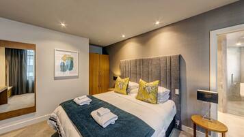 A modern hotel room with a large bed, a mirror, a wardrobe, and a shower area.
