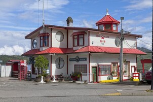 Un edificio de dos pisos con techo rojo y paredes blancas, que muestra un letrero con la inscripción 'Eagle Bluff B&B' y 'Wet Coast Lunch'.