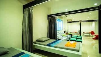 Relax in a serene space with a single bed, grey pillow, and a bathroom area featuring a mirror and sink.